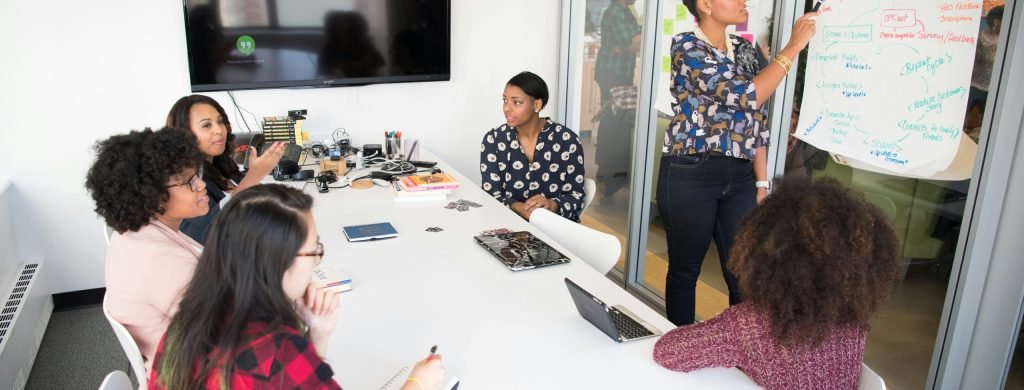 A multicultural office team engages in a collaborative brainstorming session around a conference table.