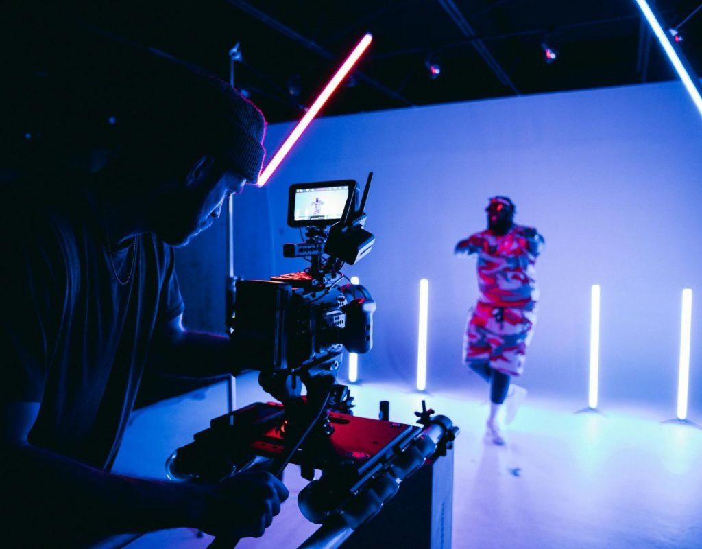 Behind-the-scenes look at a studio shoot with neon lights and camera crew.